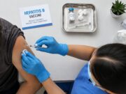 Health care worker administering a hepatitis B vaccine overhead shot
