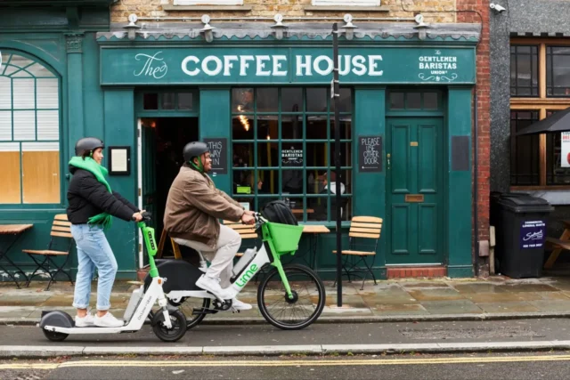 Two Lime riders using an electric scooter and e-bike outside a coffee shop