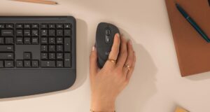 A hand resting on the Logitech Signature Comfort Plus M850 L mouse next to the keyboard