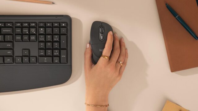 A hand resting on the Logitech Signature Comfort Plus M850 L mouse next to the keyboard