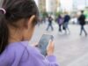 Ofcom Pushes Meta, Snap And Roblox On Child Safety Little girl using a smartphone in public for Ofcom child safety story