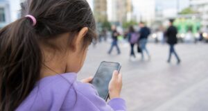 Little girl using a smartphone in public for Ofcom child safety story
