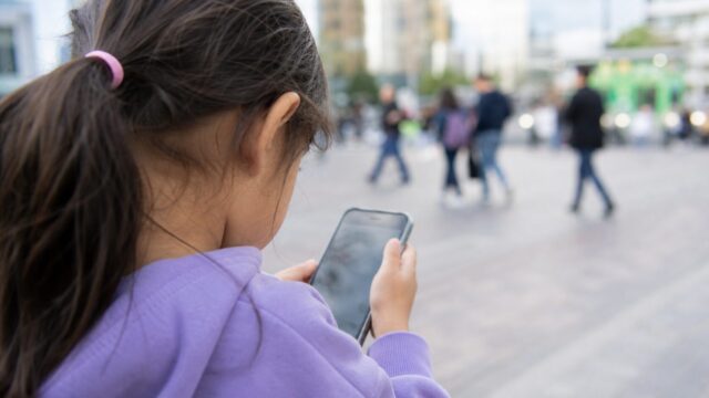 Little girl using smartphone in public Little girl using a smartphone in public for Ofcom child safety story