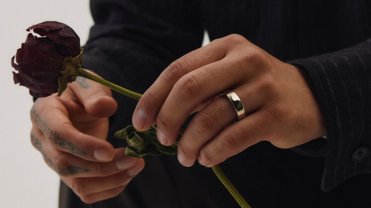 Oura Ring 5 worn on a hand while holding a dried flower