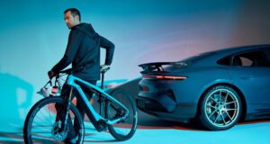 Porsche Is Shutting Down Its Performance E-Bike Division A rider on a Porsche eBike beside a Porsche Taycan Turbo GT