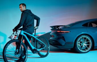 Porsche Is Shutting Down Its Performance E-Bike Division A rider on a Porsche eBike beside a Porsche Taycan Turbo GT