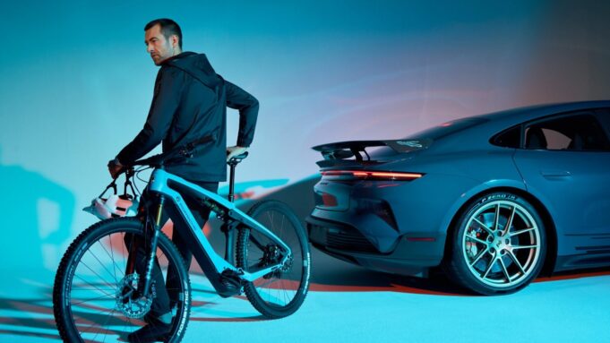 A rider on a Porsche eBike beside a Porsche Taycan Turbo GT