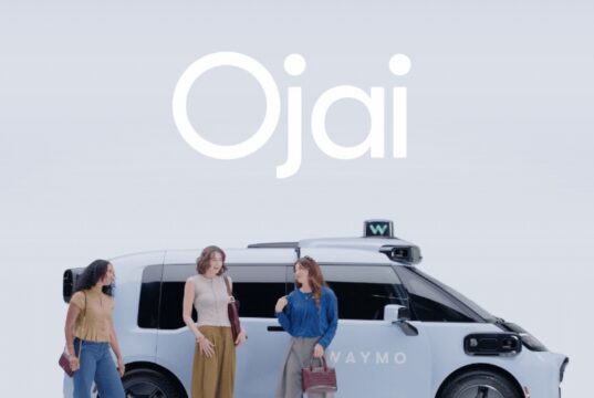 Waymo Ojai robotaxi official exterior image with riders standing beside the vehicle