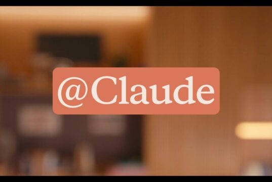Anthropic official Claude Tag announcement graphic showing the @Claude tag over a warm office setting.