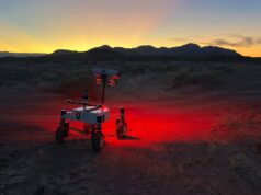 NASA's ERNEST prototype rover driving across a twilight desert landscape during field testing in Southern California.