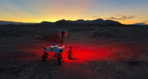 NASA's ERNEST prototype rover driving across a twilight desert landscape during field testing in Southern California.