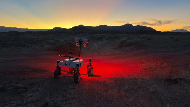 NASA's ERNEST prototype rover driving across a twilight desert landscape during field testing in Southern California.