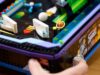 A hand plays the LEGO Icons Arcade Pinball Machine, LEGO set 11374, showing its working launcher and tabletop arcade design.