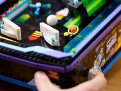 A hand plays the LEGO Icons Arcade Pinball Machine, LEGO set 11374, showing its working launcher and tabletop arcade design.