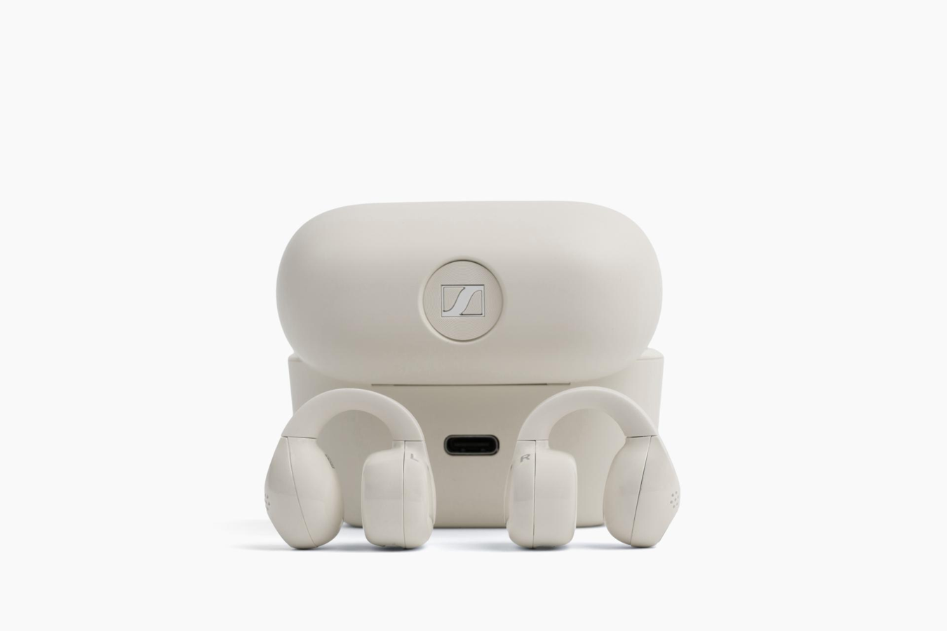 Cream Sennheiser ACCENTUM Clip earbuds placed in front of their charging case.