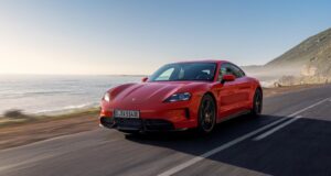 Red Porsche Taycan driving on a coastal road.