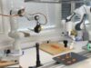 The Sashimi-Bot robot chef prepares slices of raw salmon on a cutting board.