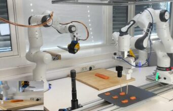 The Sashimi-Bot robot chef prepares slices of raw salmon on a cutting board.