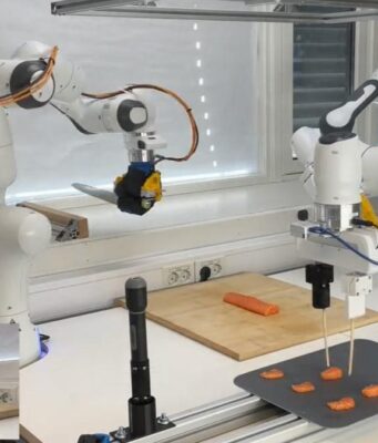 The Sashimi-Bot robot chef prepares slices of raw salmon on a cutting board.