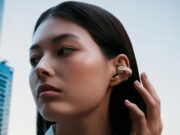 Sennheiser ACCENTUM Clip Takes Open-Ear Earbuds Into LDAC Territory Person wearing cream Sennheiser ACCENTUM Clip open-ear earbuds on a city street.