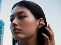 Person wearing cream Sennheiser ACCENTUM Clip open-ear earbuds on a city street.