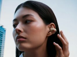 Person wearing cream Sennheiser ACCENTUM Clip open-ear earbuds on a city street.