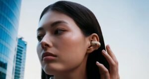 Person wearing cream Sennheiser ACCENTUM Clip open-ear earbuds on a city street.