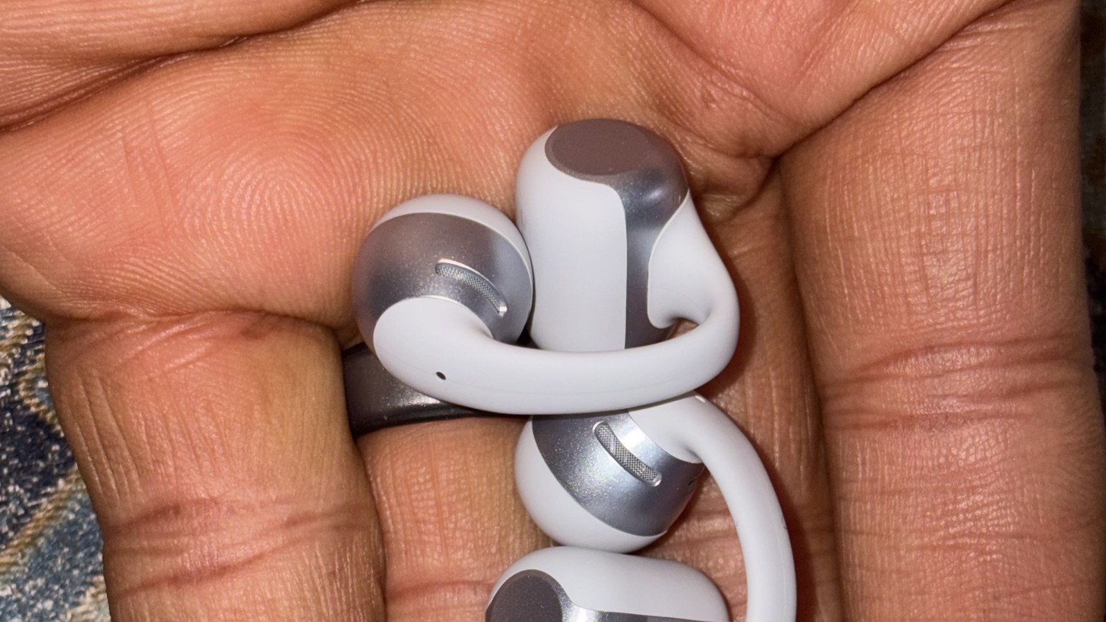 Shokz OpenDots 2 earbuds shown in hand in 16:9 format