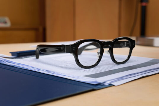 Halliday G2 AI glasses resting on documents on a desk