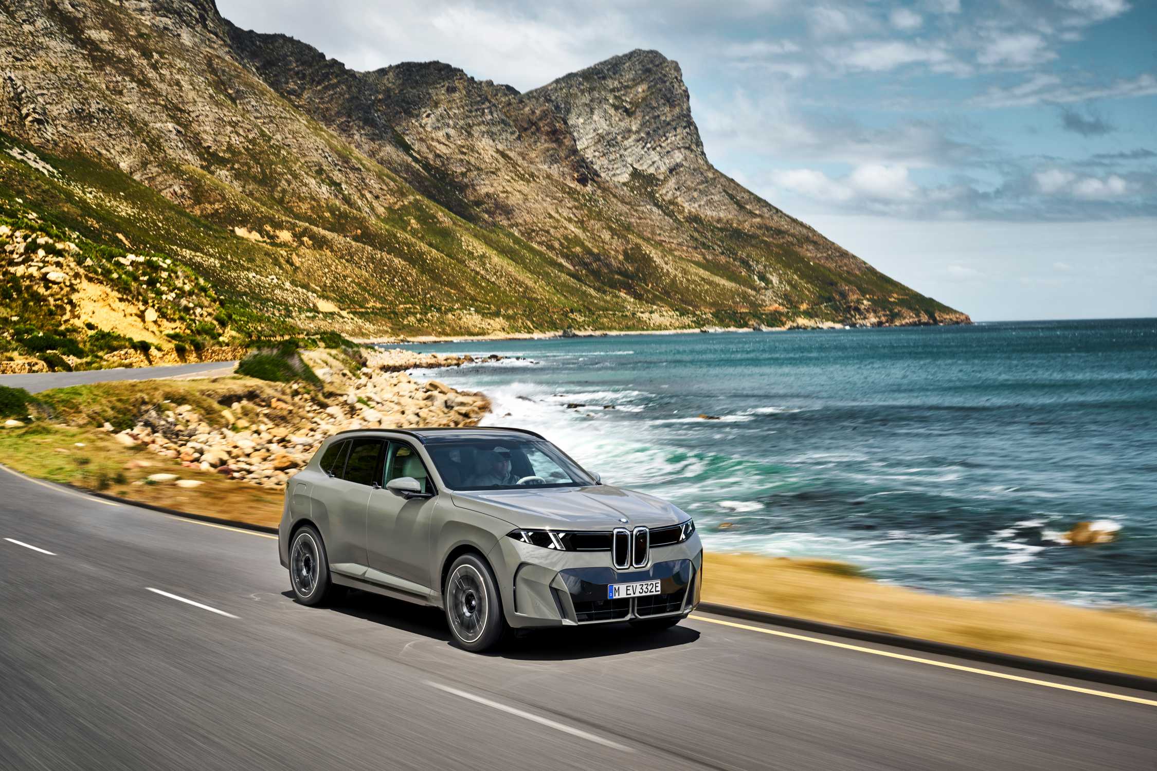 BMW iX5 60 xDrive driving on a coastal road in an official BMW press image
