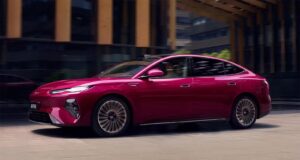 BYD Seal 08 sedan in magenta finish, side profile driving through a city street