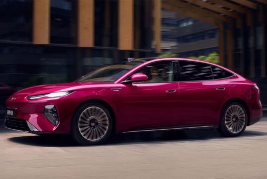 BYD Seal 08 sedan in magenta finish, side profile driving through a city street