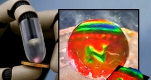 Robot finger pressing a coin next to the mechanochromic tactile sensor showing the coin's imprint as color patterns