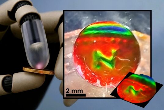 Robot finger pressing a coin next to the mechanochromic tactile sensor showing the coin's imprint as color patterns