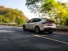 Tesla Model Y Long Wheelbase Brings Six Seats to the US for $61,990 Tesla Model Y Long Wheelbase driving on a tree-lined road, rear three-quarter view