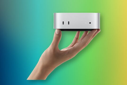 A hand holding Apple M6 Mac mini with its front USB-C ports and headphone jack
