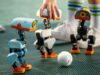 Pollen Robotics Microduck Opens Preorders at 399 Dollars Three Microduck robots on a turf pitch around a small ball, with a hand steadying one unit
