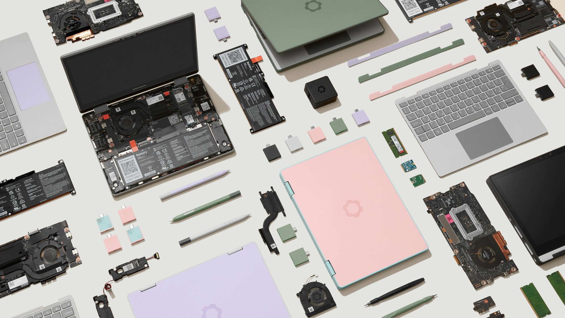 Disassembled Framework Laptop 12 parts, boards, batteries, and color covers on a table