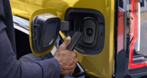 Official GM photo of a NACS charger plug at the charge port of a yellow GMC Hummer EV