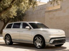 Cream Genesis GV90 three-quarter front view beside a stone wall and olive tree