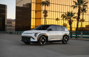 Kia EV3 Starts at $29,890 as Kia’s Cheapest US Electric SUV White 2027 Kia EV3 parked in front of a gold-glass office building at sunset