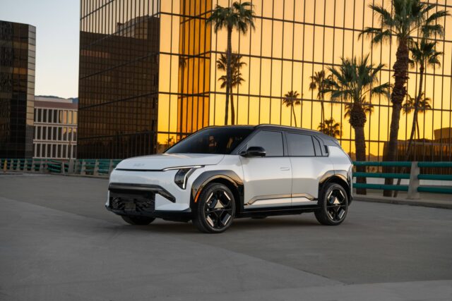 kia-ev3-featured White 2027 Kia EV3 parked in front of a gold-glass office building at sunset