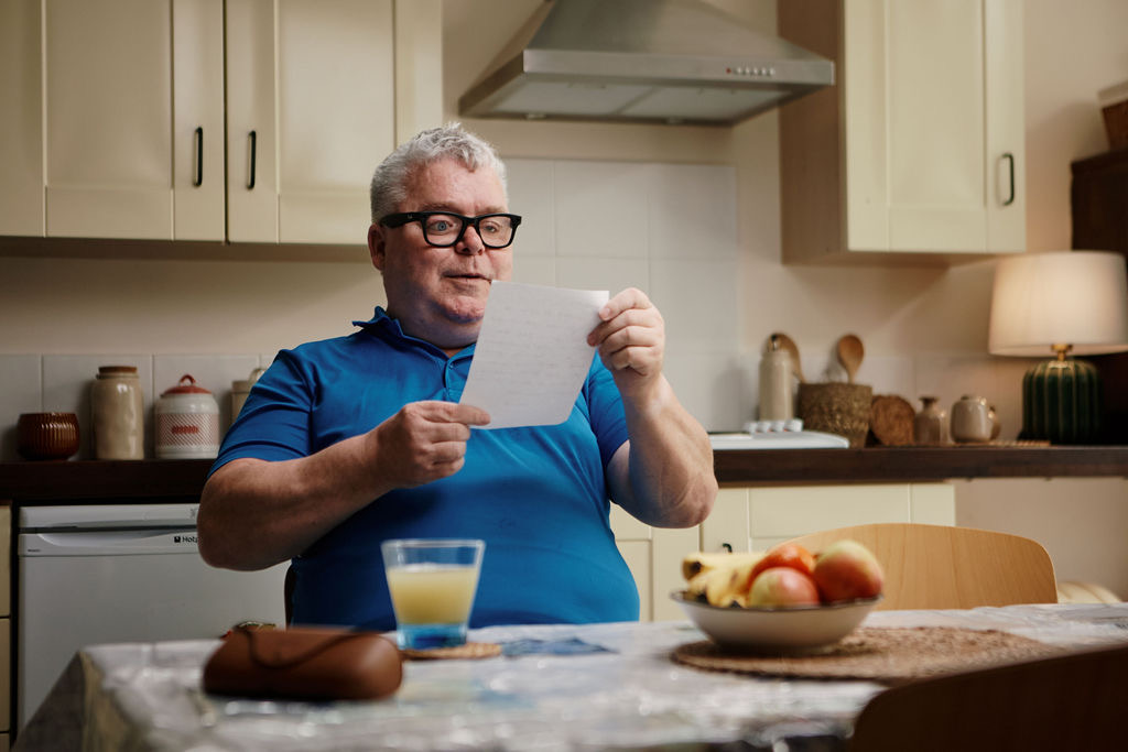 A Vision Ireland participant wears Ray-Ban Meta glasses and reads a letter at a kitchen table