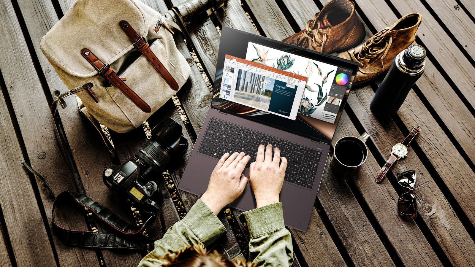 Acer Vero 16 laptop open on a wooden table surrounded by a camera, backpack and travel gear