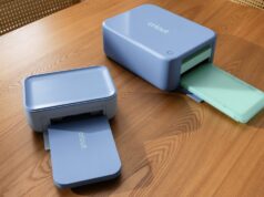 Cricut StickerPix Print and Print + Cut machines on a wooden table with output trays open