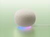 White Google Home Speaker on a mint backdrop with a blue-to-purple light ring and power cable