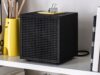 IKEA Badkruka Speaker: $59.99 Wired Bluetooth Audio Black IKEA Badkruka cube speaker on a white shelf between books and a yellow pencil holder, with its power cable behind it