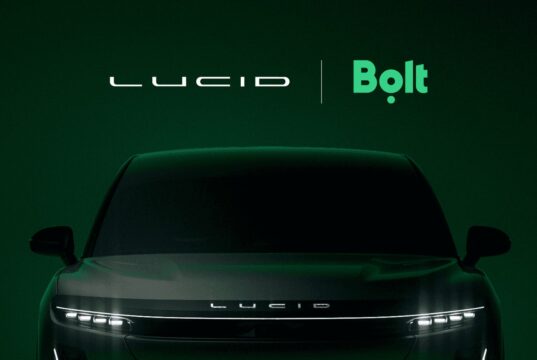 Lucid and Bolt logos above the front of a dark Lucid SUV on a deep green background