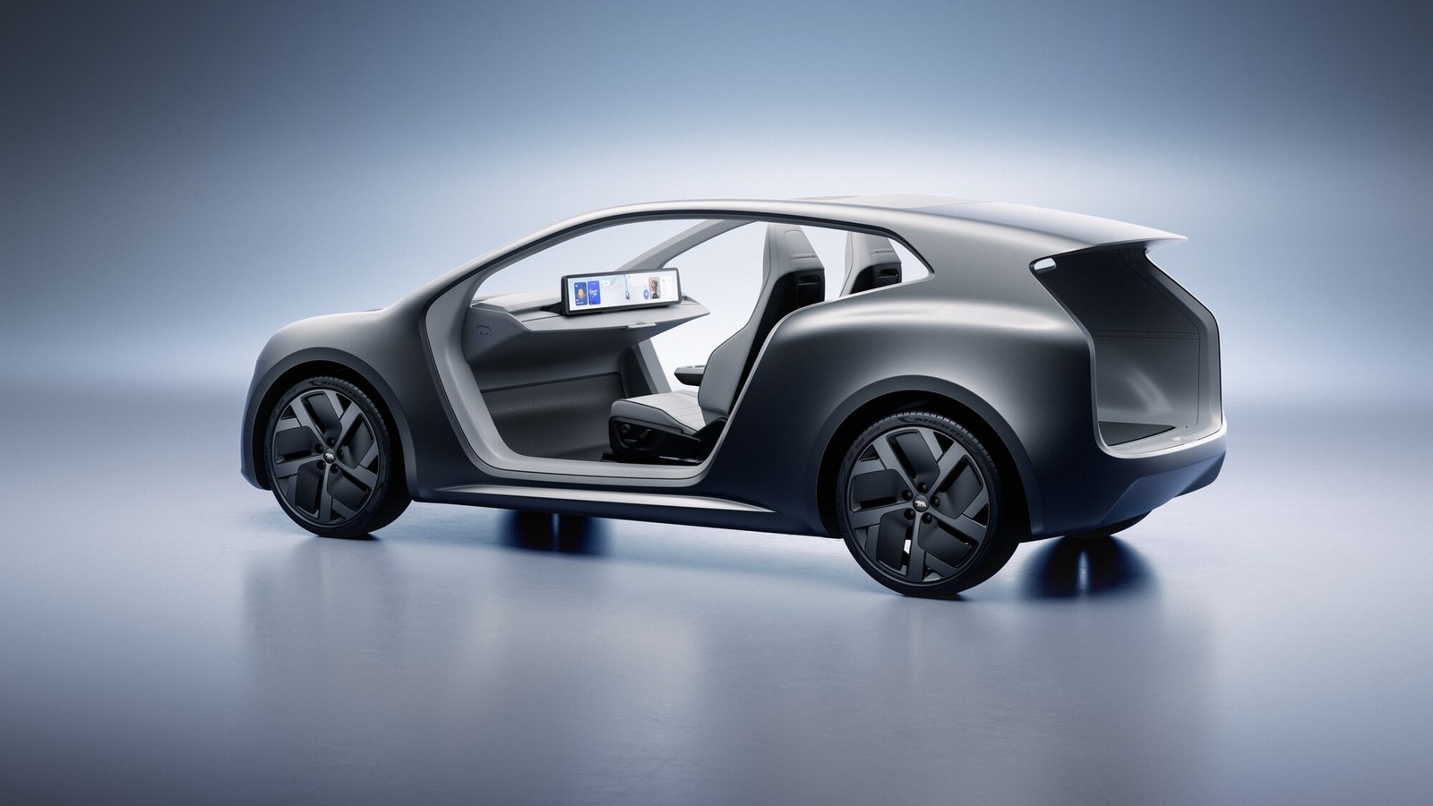 Lucid Lunar two-seat robotaxi concept in matte grey, seen from the rear quarter with its side open to show two seats and a dashboard screen