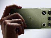 Motorola Signature 27 in PANTONE Capulet Olive held in hand, showing its quad camera housing with B&O branding